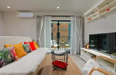a living room with a white couch with colorful pillows at 1 BR apartment in Title Naiyang in Nai Yang Beach
