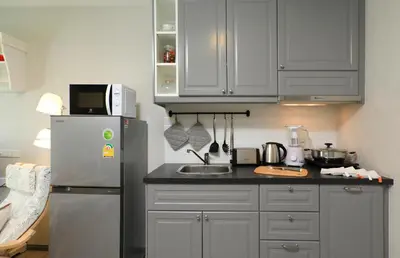 a kitchen with white cabinets and a refrigerator at 1 BR apartment in Title Naiyang in Nai Yang Beach
