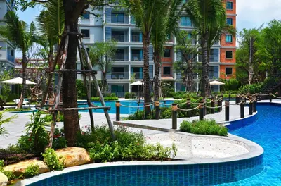 a resort with a pool with palm trees and a building at 1 BR apartment in Title Naiyang in Nai Yang Beach
