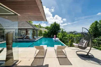 a swimming pool with chairs next to a house at \u5c71\u6d77\u306e\u5922 1600\u5e73\u8c6a\u534e\u79c1\u4eba\u6cf3\u6c60\u522b\u5885 15m\u8d85\u5927\u6cf3\u6c60 \u6b65\u884c\u6d77\u8fb9 \u514d\u8d39\u65e9\u9910 \u4f63\u4eba in Phuket Town