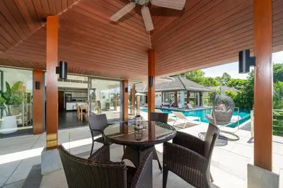 a patio with a table and chairs and a pool at \u5c71\u6d77\u306e\u5922 1600\u5e73\u8c6a\u534e\u79c1\u4eba\u6cf3\u6c60\u522b\u5885 15m\u8d85\u5927\u6cf3\u6c60 \u6b65\u884c\u6d77\u8fb9 \u514d\u8d39\u65e9\u9910 \u4f63\u4eba in Phuket Town