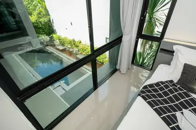a bedroom with a view of a swimming pool through windows at \u6668\u6d77\u306e\u5922\u4e09\u5367\u79c1\u4eba\u82b1\u56ed\u6cf3\u6c60\u522b\u5885 in Ban Pak Lak