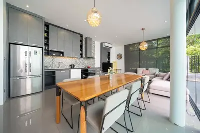 a kitchen and living room with a wooden table and chairs at \u6668\u6d77\u306e\u5922\u4e09\u5367\u79c1\u4eba\u82b1\u56ed\u6cf3\u6c60\u522b\u5885 in Ban Pak Lak