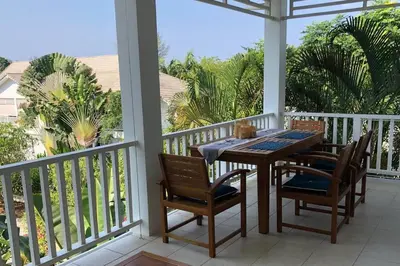 a porch with a table and chairs and palm trees at Ocean breeze studio 1 bed in Ban Pak Lak