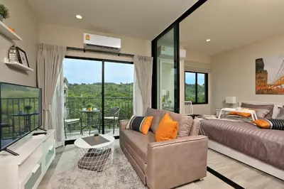 a bedroom with a bed and a couch and a balcony at 300 m to Naiyang Beach by Capital Pro in Nai Yang Beach