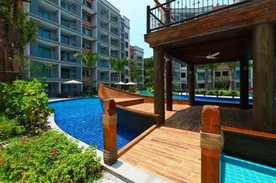 a swimming pool with a wooden deck next to a building at 300 m to Naiyang Beach by Capital Pro in Nai Yang Beach