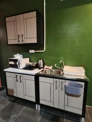 a kitchen with white cabinets and a sink and a green wall at Bonanza Patong Beach2 for 2 BR 100m to Beach Grace Room in Patong Beach