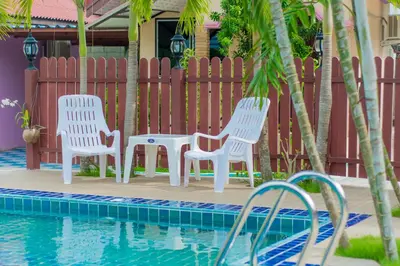 two white chairs and a table next to a swimming pool at Phaithong Sotel Resort in Chalong