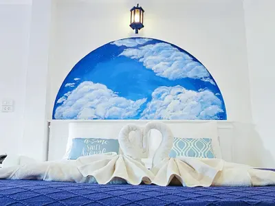two swans laying on a bed in front of a mural at Phaithong Sotel Resort in Chalong