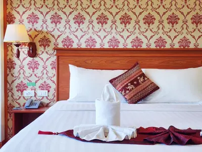 a bedroom with a white bed with a red and gold wallpaper at Phaithong Sotel Resort in Chalong
