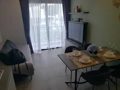 a living room with a table and chairs and a television at Chalong Pier apartement in Phuket Town