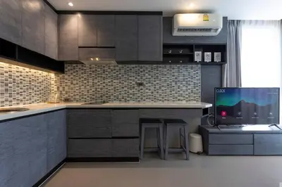 a kitchen with gray cabinets and a tv in it at Fully Loaded Resort everything You Need #C142 in Kamala Beach