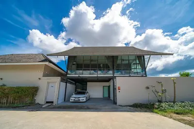 a house with a car parked in the driveway at BangTao 6-bedroom villa 18 meters, competition-grade swimming pool, industrial style design aesthetic, gaming and entertainment floor, suitable for family vacations and group gatherings in Bang Tao Beach