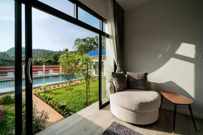 a living room with a chair and a large window at Pool Villa Alawan Krabi Klong Muang R2 in Klong Muang Beach