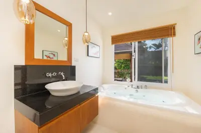 a bathroom with a tub and a sink and a mirror at Kokyang Estate by TropicLook in Nai Harn Beach