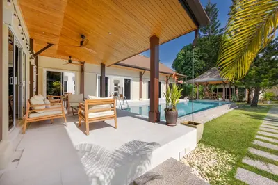 an outdoor patio with chairs and a swimming pool at Kokyang Estate by TropicLook in Nai Harn Beach