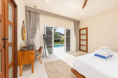 a bedroom with a bed and a desk and a pool at Kokyang Estate by TropicLook in Nai Harn Beach