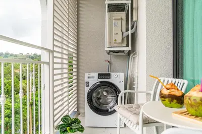 a washing machine in a room with a table at Title Halo Modern Line Pool View Gym Sauna in Nai Yang Beach