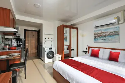 a bedroom with a large bed and a kitchen at Studio 777 Condo MaiKhao in Ban Mai Salae