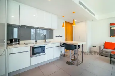 a kitchen with white cabinets and a table and a couch at Oceanstone Condo 2 bedrooms BangTao Laguna in Bang Tao Beach