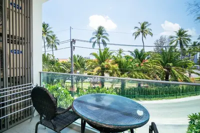 a balcony with a table and chairs and palm trees at Oceanstone Condo 2 bedrooms BangTao Laguna in Bang Tao Beach