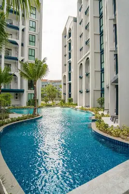 a swimming pool in the middle of two tall buildings at Title Halo I Sea You Naiyang Pool Gym Sauna in Nai Yang Beach