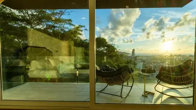 a living room with a view of the city from a window at Patong 180-degree stunning sea view modern 4-bedroom villa sleeps 10 private pool stunning sunset BBQ in Patong Beach