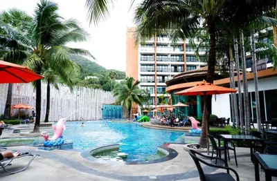 a swimming pool with people in a resort with palm trees at the beach height resort by sahana in Kata Beach