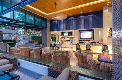 a restaurant with chairs and a bar with a tv at the beach height resort by sahana in Kata Beach