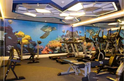 a gym with an aquarium themed room with tread machines at the beach height resort by sahana in Kata Beach