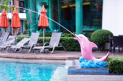 a pink dolphin statue next to a swimming pool at the beach height resort by sahana in Kata Beach