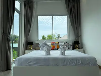 a bedroom with a white bed with a window at Kamala Evergreen Home in Kamala Beach