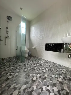 a bathroom with a toilet and a glass shower at Kamala Evergreen Home in Kamala Beach