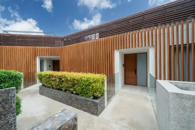 a facade of a building with two doors and bushes at Ocean Bliss - Sapphire Bay 3BR Apartment 812 with Terrace and Awe-Inspiring Views of Patong Bay in Patong Beach