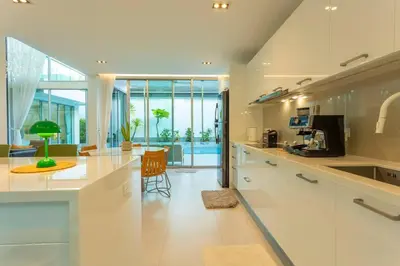 a kitchen with white cabinets and a table with a chair at Nicest In Phuket 4Br 1 km Bang Tao Beach V141 in Bang Tao Beach