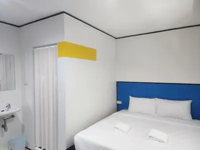 a bedroom with a bed with a blue headboard and a sink at RYB Hostel Phuket in Ban Lo Long