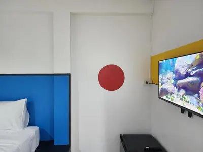 a bedroom with a bed and a flat screen tv on a wall at RYB Hostel Phuket in Ban Lo Long