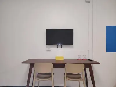 a wooden table with two chairs and a tv on a wall at RYB Hostel Phuket in Ban Lo Long