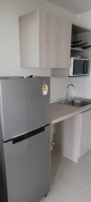 a small kitchen with a refrigerator and a sink at Centrally located new and affordable condo for the first mover in Ban Ket Ho