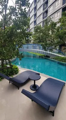 a pool with a table and chairs in front of a building at Centrally located new and affordable condo for the first mover in Ban Ket Ho