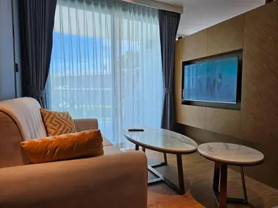 a living room with a couch and a table and a tv at La Vita Stylish apartment in 5 star hotel in Rawai Beach