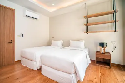 two beds in a room with white walls and wooden floors at Banyan Tree Grand Residences by Banyan Living in Phuket Town