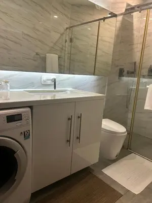 a bathroom with a sink and a washing machine at Oceana Kamala Stunning corner Suite Sea View in Kamala Beach