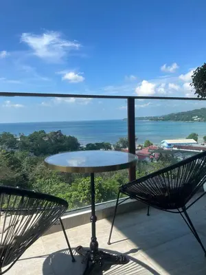 a table and chairs on a balcony with a view of the ocean at Oceana Kamala Stunning corner Suite Sea View in Kamala Beach