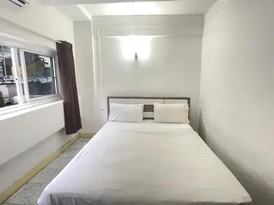 a white bed in a room with a window at Nice to CU Guest house in Patong Beach