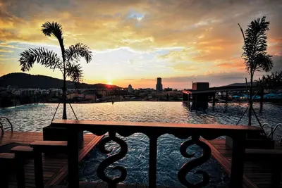 a sunset over a body of water with a table at Villa Noon in Patong Beach