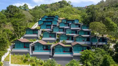 a building with blue windows on a hill at Villa Noon in Patong Beach