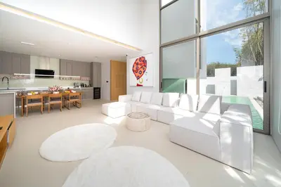 a living room with white furniture and a kitchen at Sofia Villa Phuket in Phuket Town