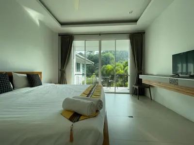 a bedroom with a bed with a television and a balcony at Little Kamala Hill in Kamala Beach