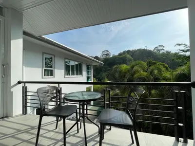a balcony with chairs and a table and a view at Little Kamala Hill in Kamala Beach